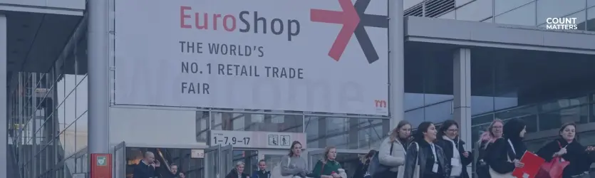 Besucher, die vor der EuroShop, der weltweit führenden Einzelhandelsmesse, spazieren gehen. Ideal für die Veranschaulichung von Analysen zur Besucherfrequenz und Einblicken in die Einzelhandelsbranche mit CountMatters, Logo in der Ecke.